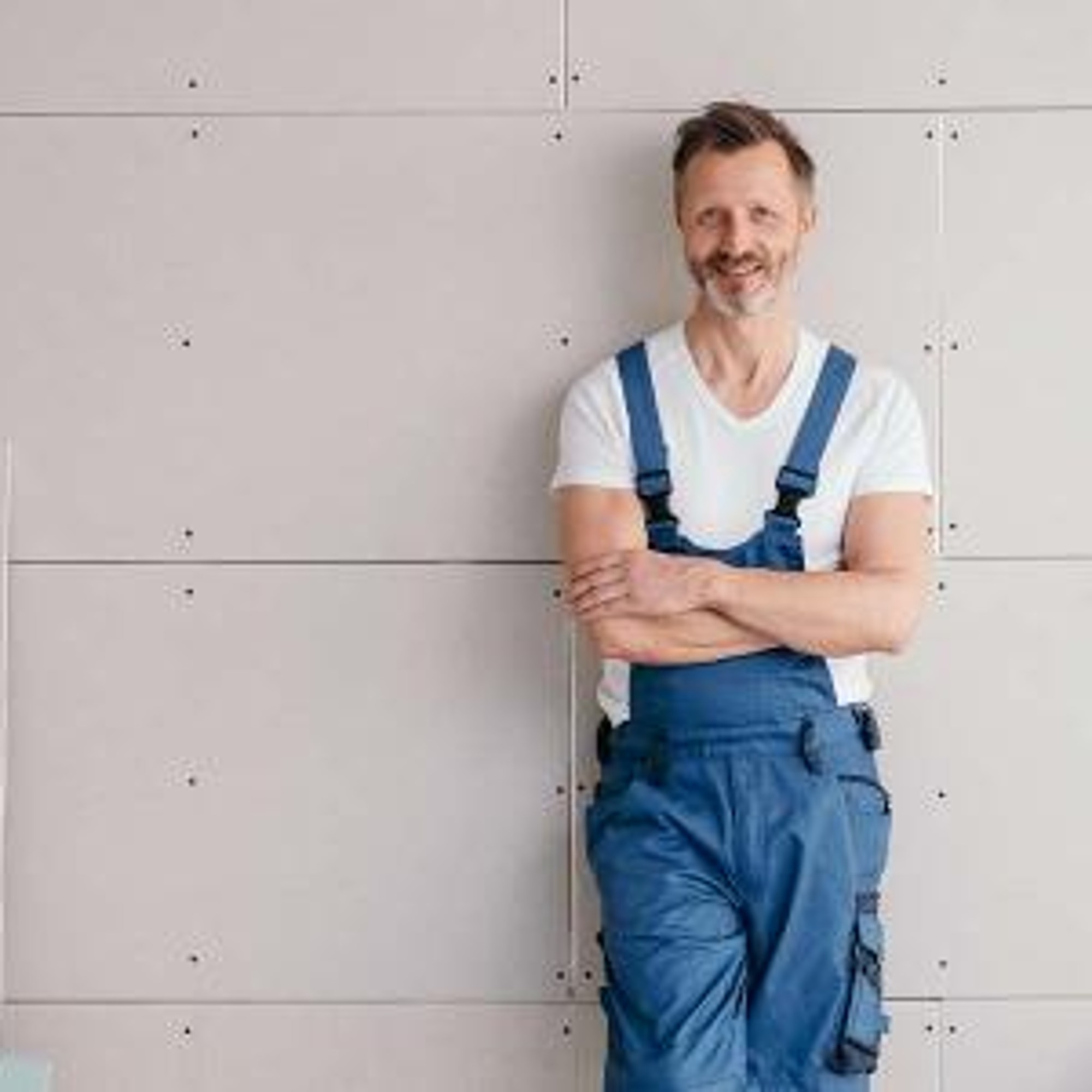 Handwerker der an einer Wand lehnt.