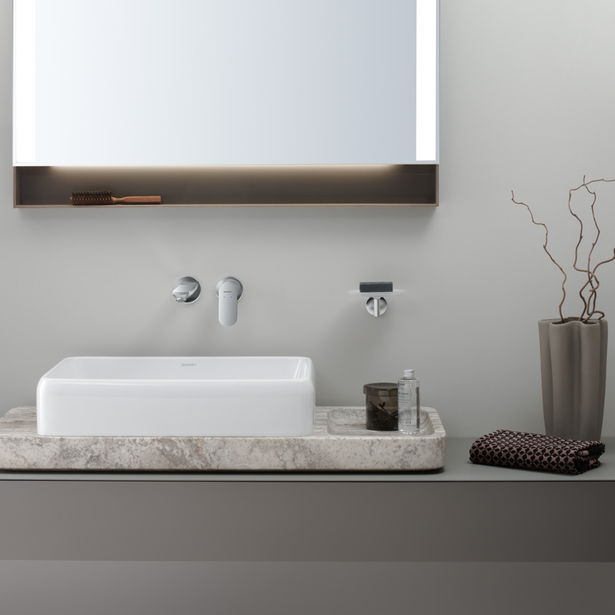 Una consolle in pietra naturale su cui è posizionato un lavabo bianco, sopra il quale è appeso uno specchio.