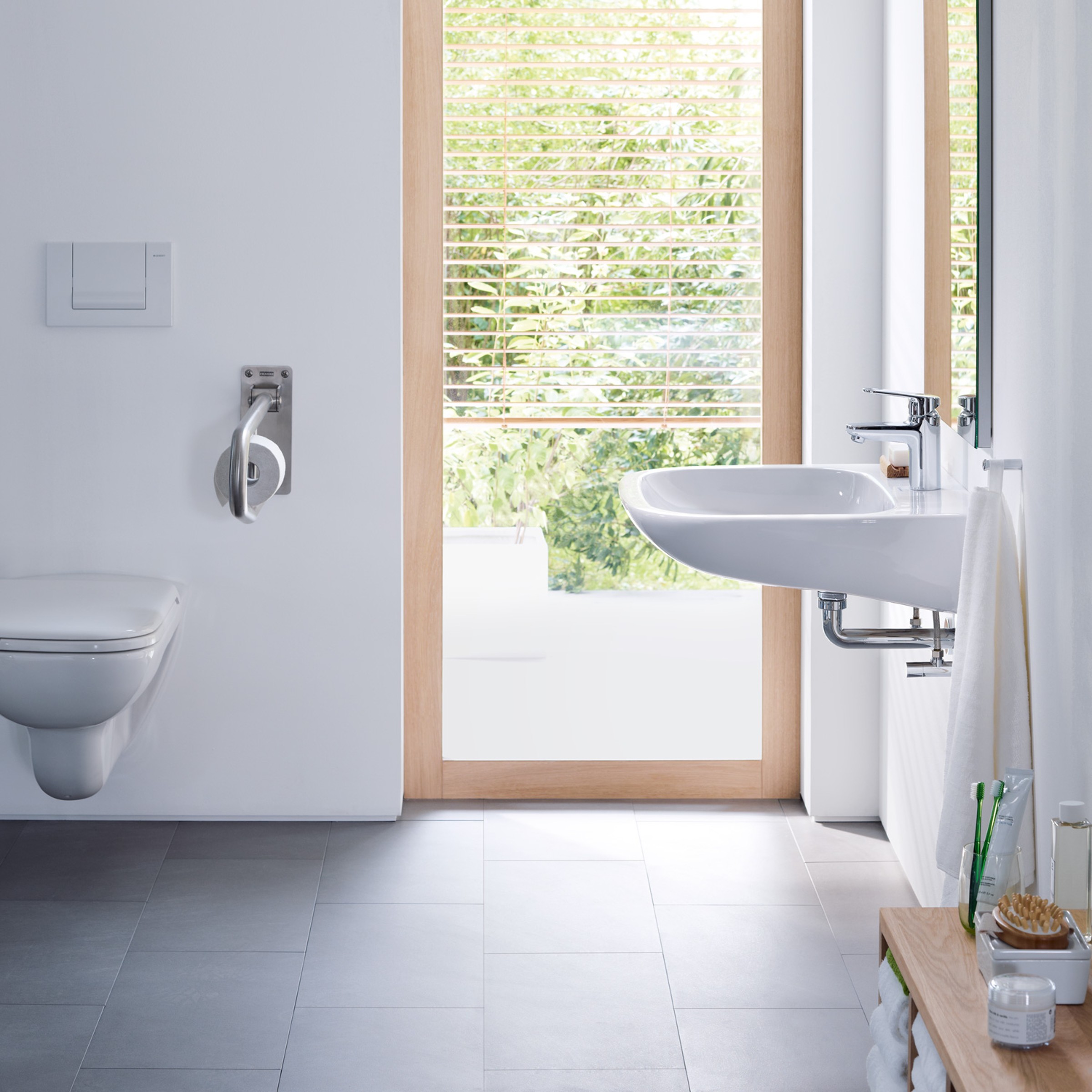  A barrier-free bathroom. A white toilet with side grab bars and a wheelchair-accessible sink.