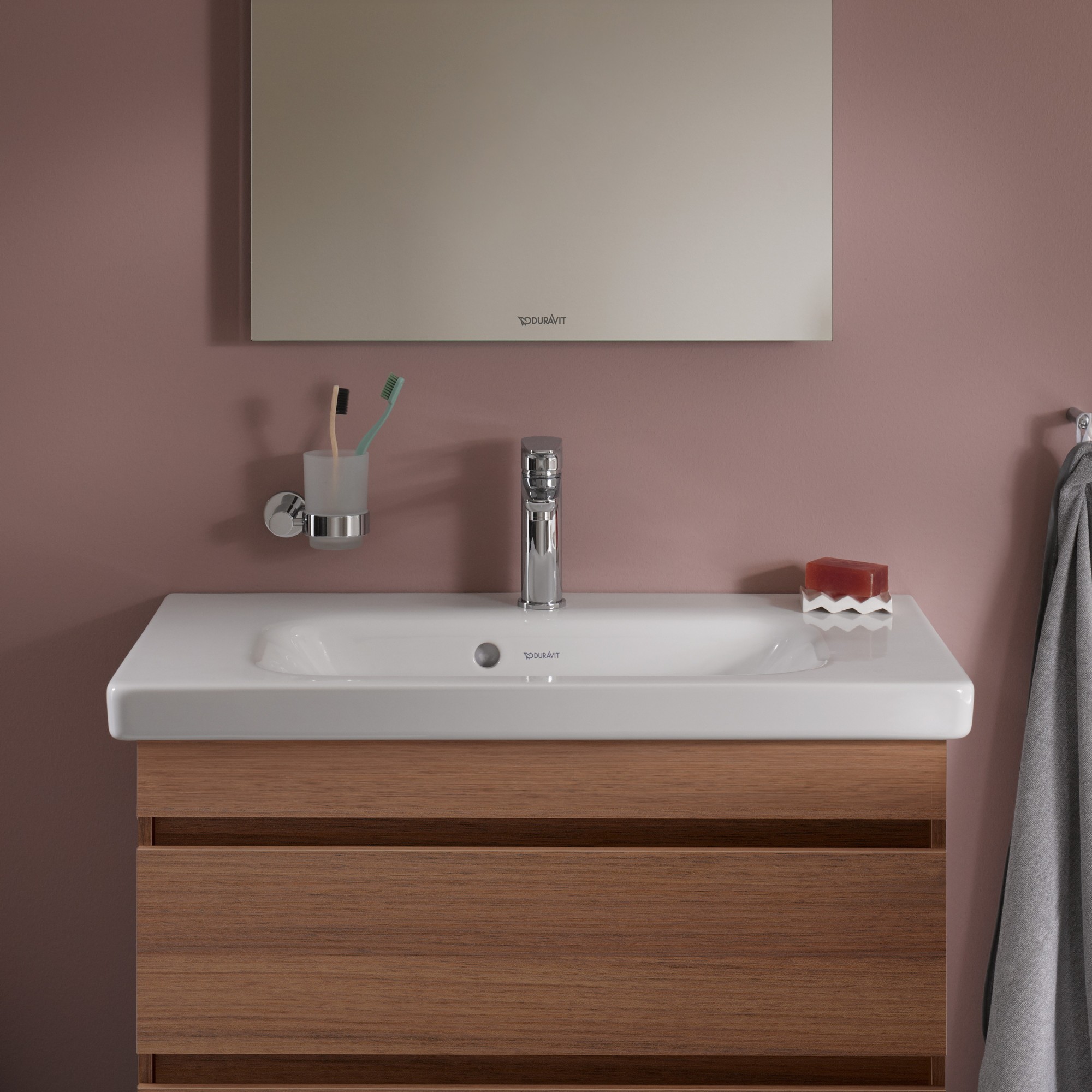 Duravit DuraStyle sink, surrounded by toothbrush, toothpaste tube, and soap, mounted on light pink bathroom wall.