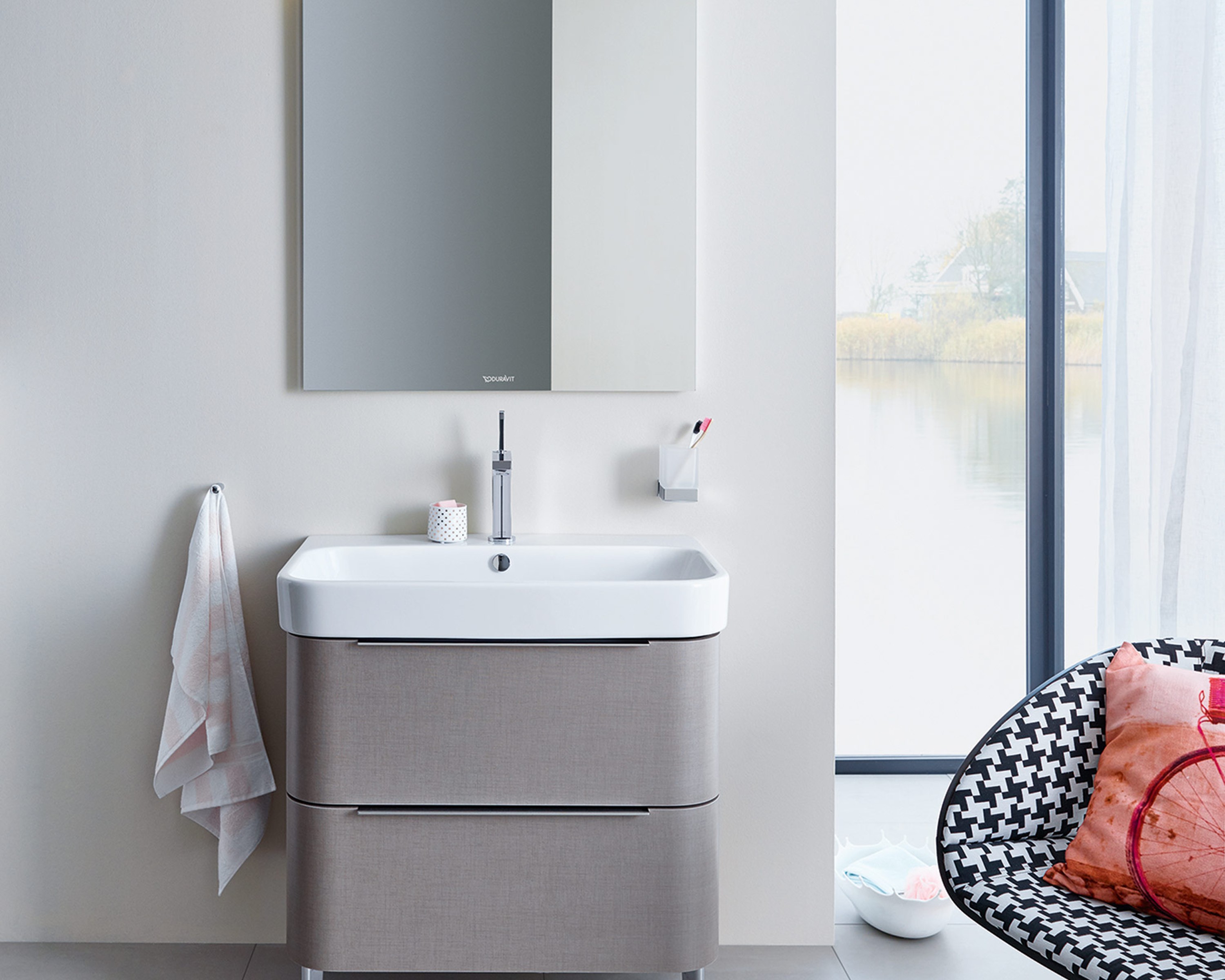 Duravit Happy D.2 bathroom furniture with mirror, surrounded by modern furnishings and a large window, exudes tranquility.