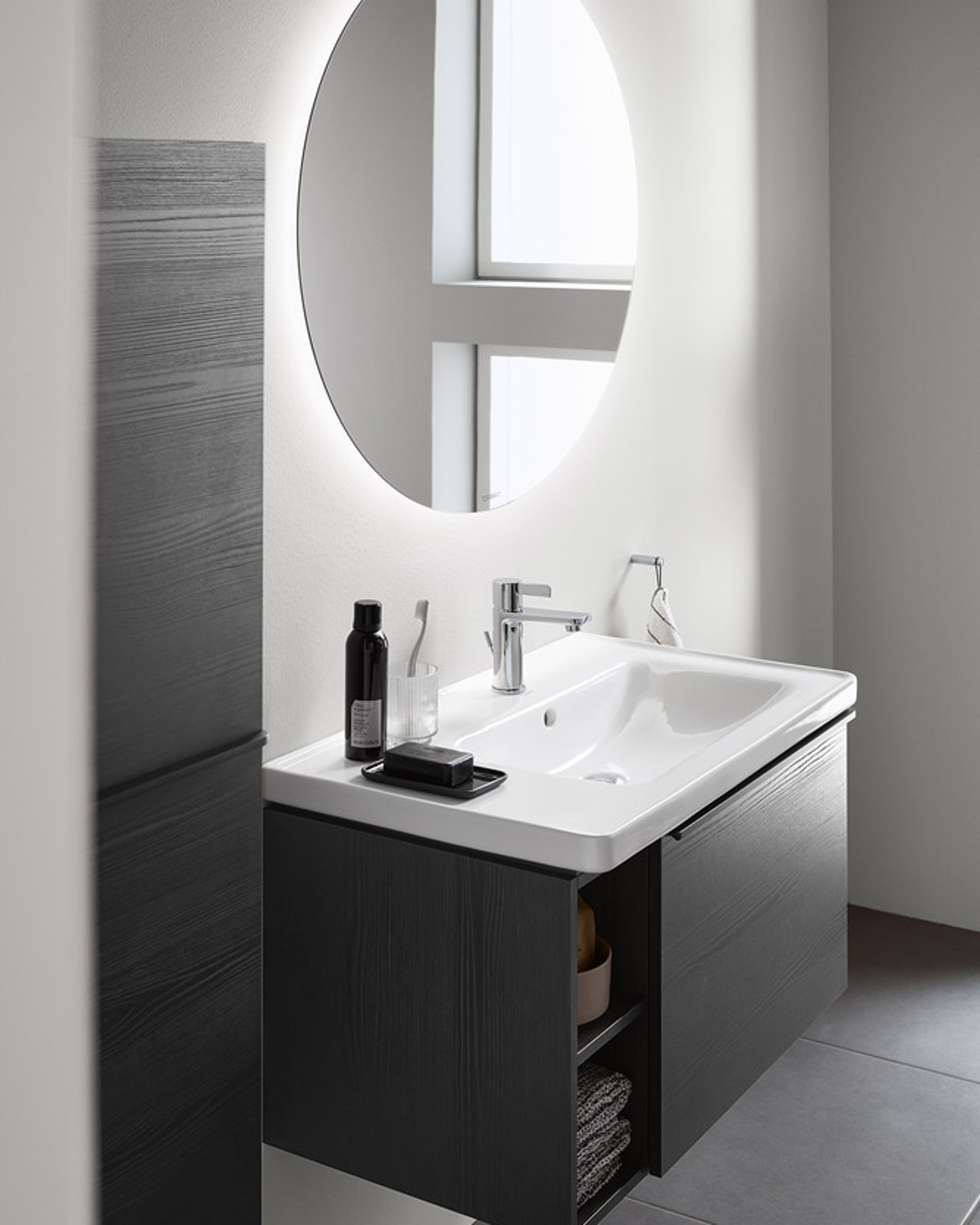 Duravit D-Neo sink with mirror, black vanity unit, and chrome-colored faucets in a bright bathroom.