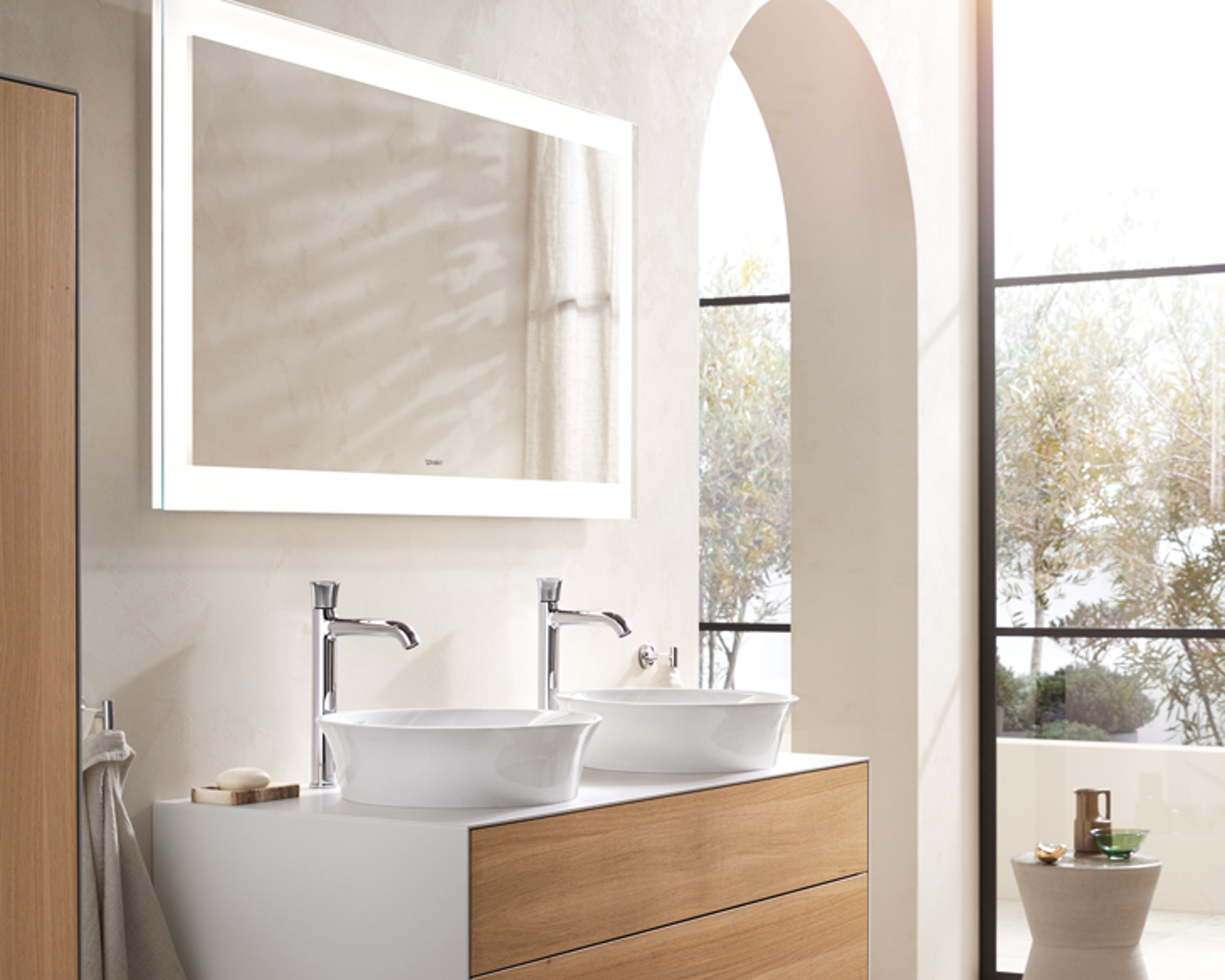Duravit bathroom furniture with two White Tulip sinks in front of an illuminated mirror, in a bright, elegant bathroom.