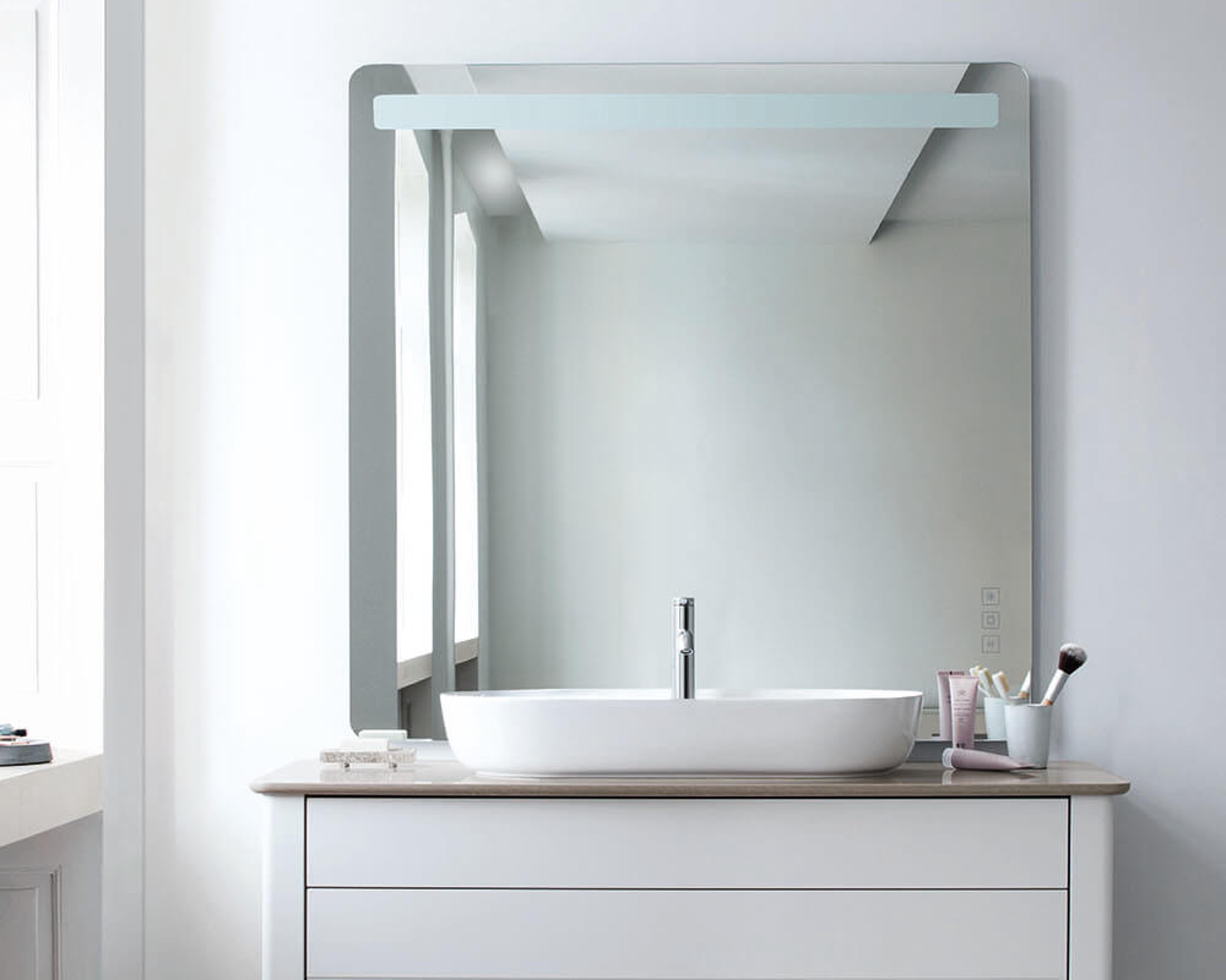 Duravit Luv vanity with mirror in a modern bathroom. Towels and toiletries are displayed on the shelf in a bright setting.