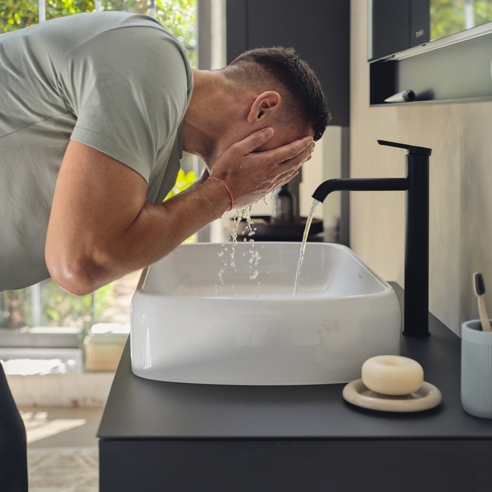 Person wäscht sich das Gesicht an einem Waschbecken