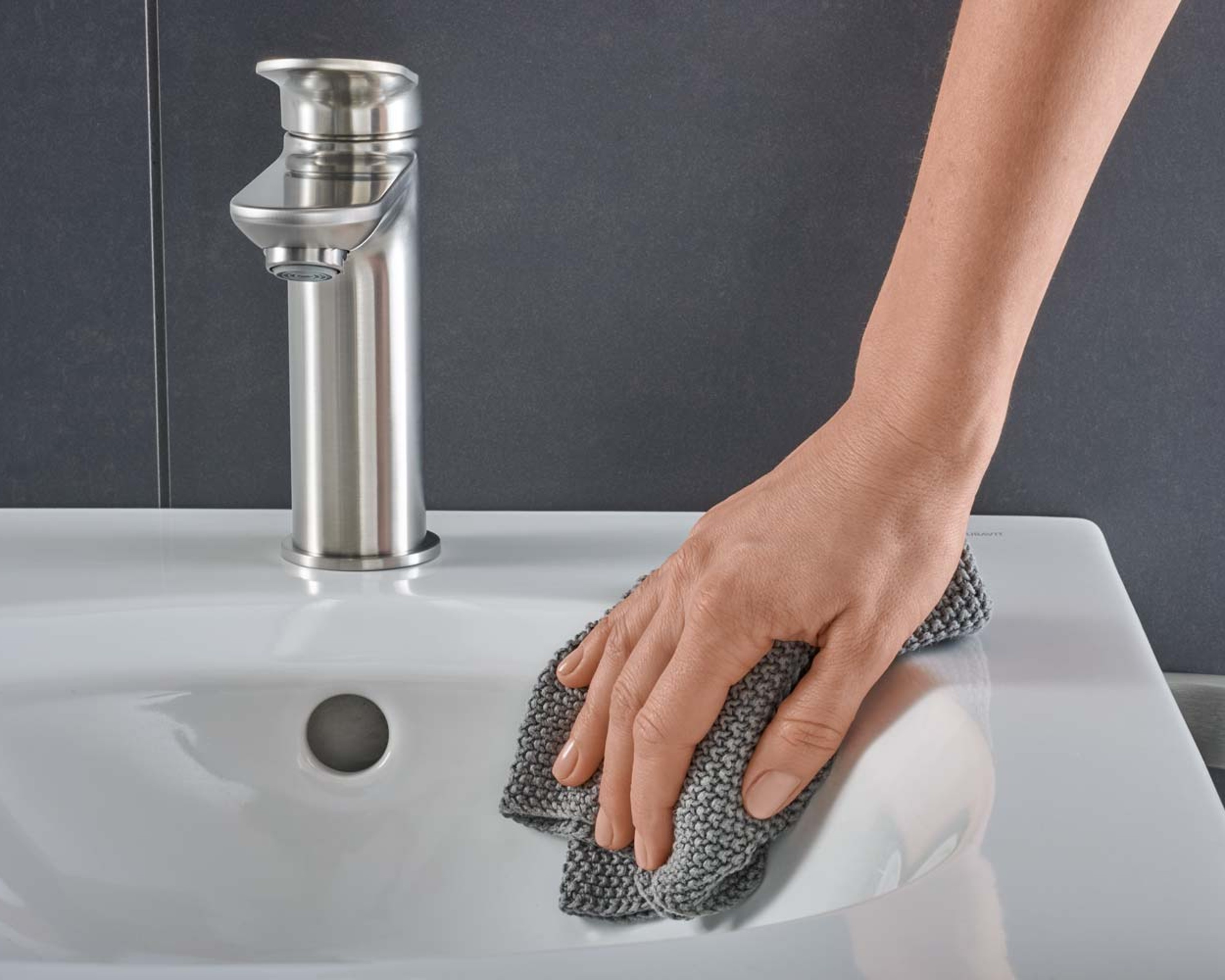 Hand mit Waschlappen putzt ein Duravit Aurena Waschbecken