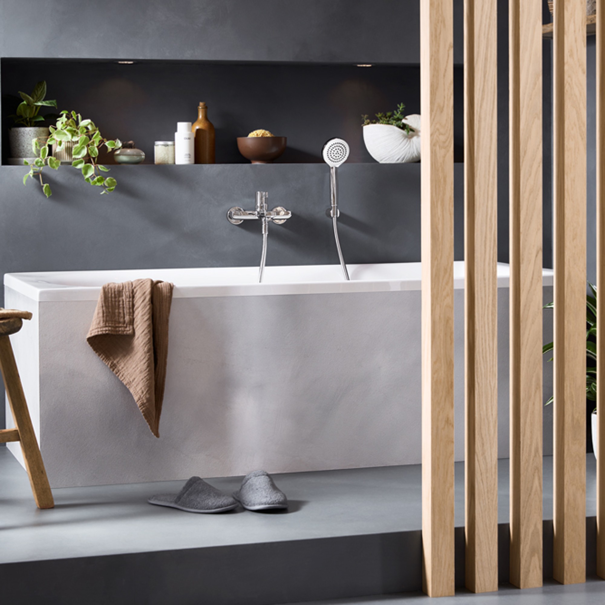 Bathroom with Duravit D-Neo bathtub in front of a gray wall, with a wooden partition in front of it.