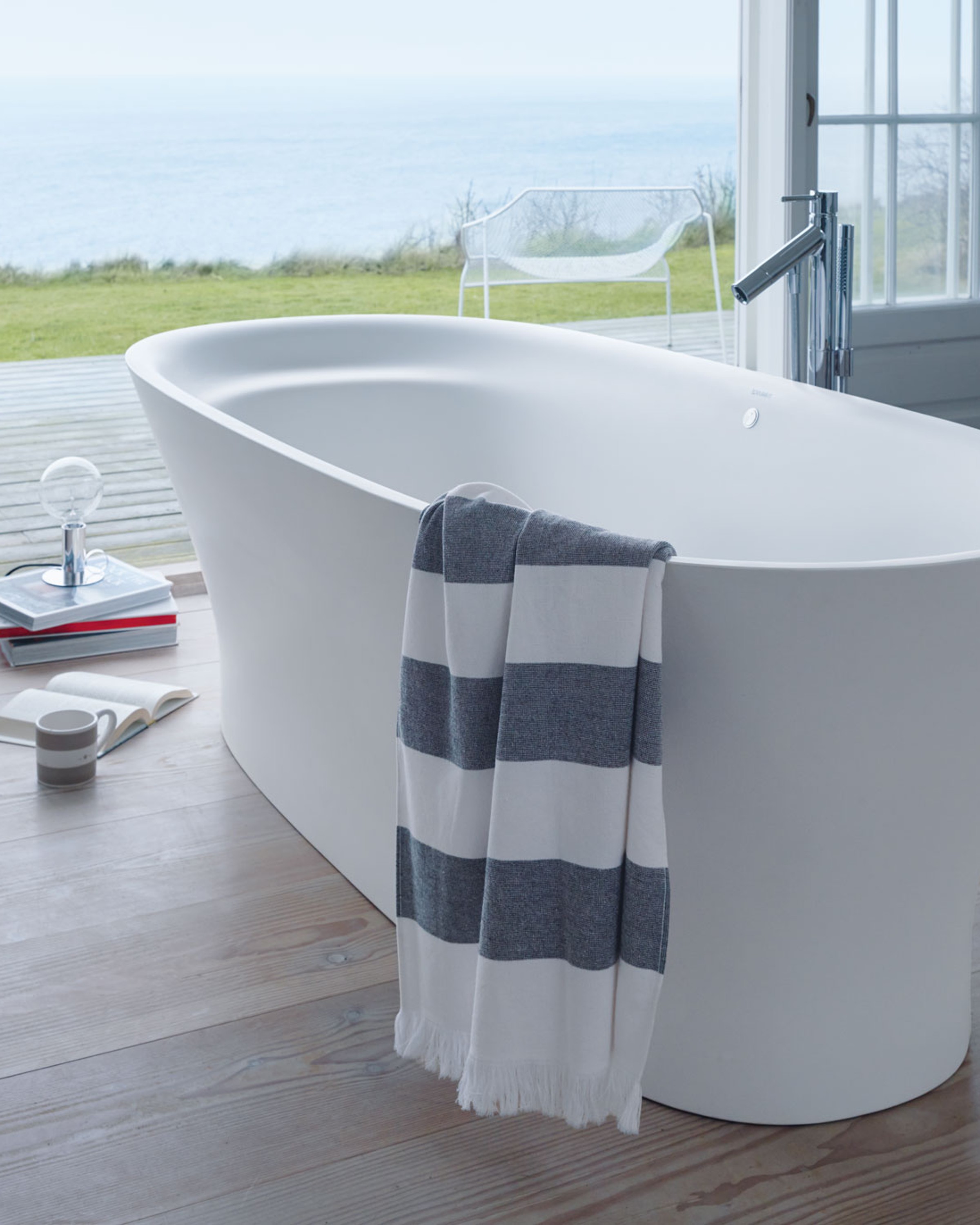 Freistehende Badewanne der Serie Duravit Cape Cod vor einer Terrasse mit Meerblick