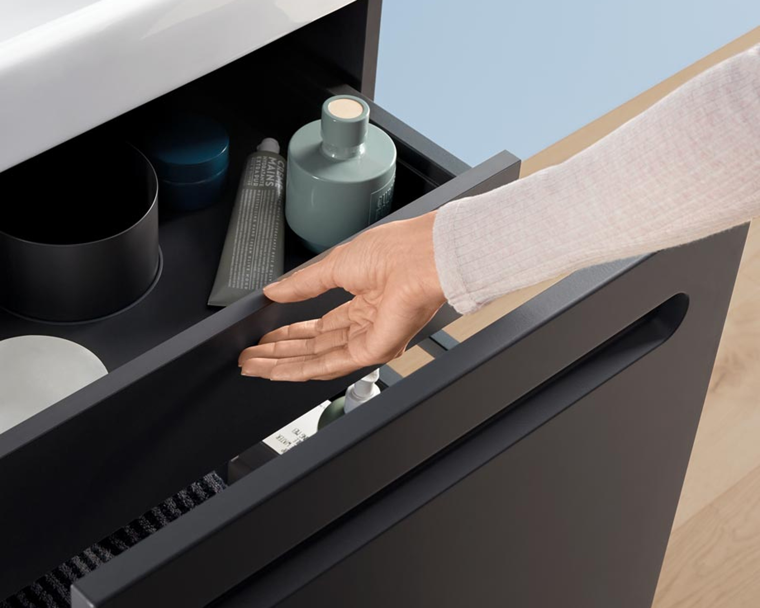 Hand öffnet Schublade eines Waschtischunterschranks
