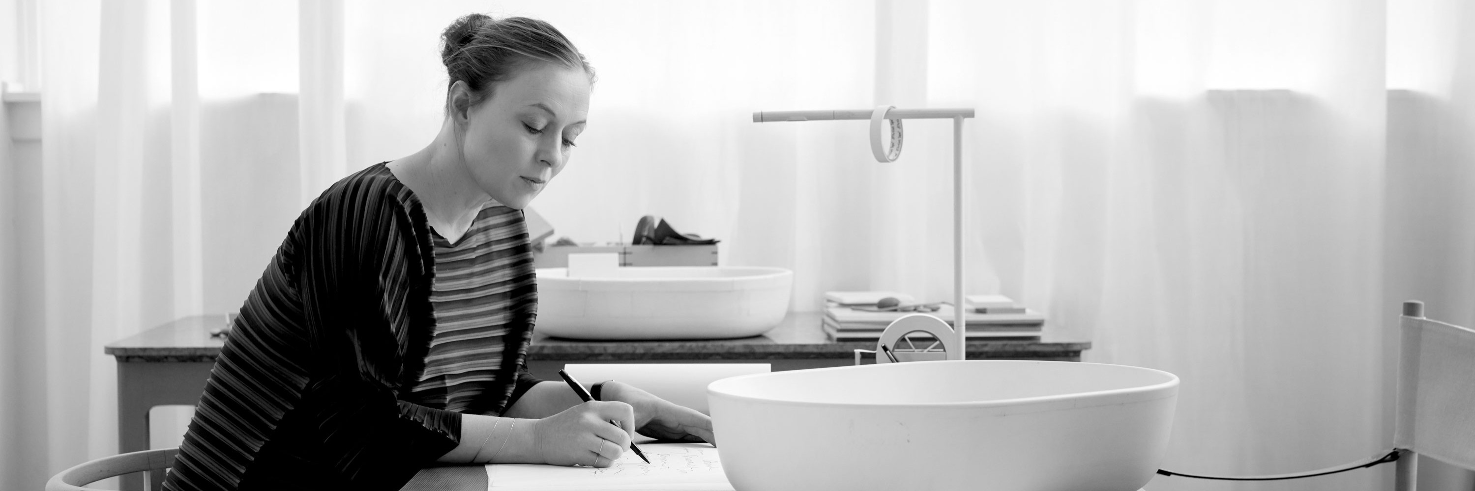 Designerin Cecilie Manz sitzt an einem Schreibtisch und entwickelt Duravit Produkt