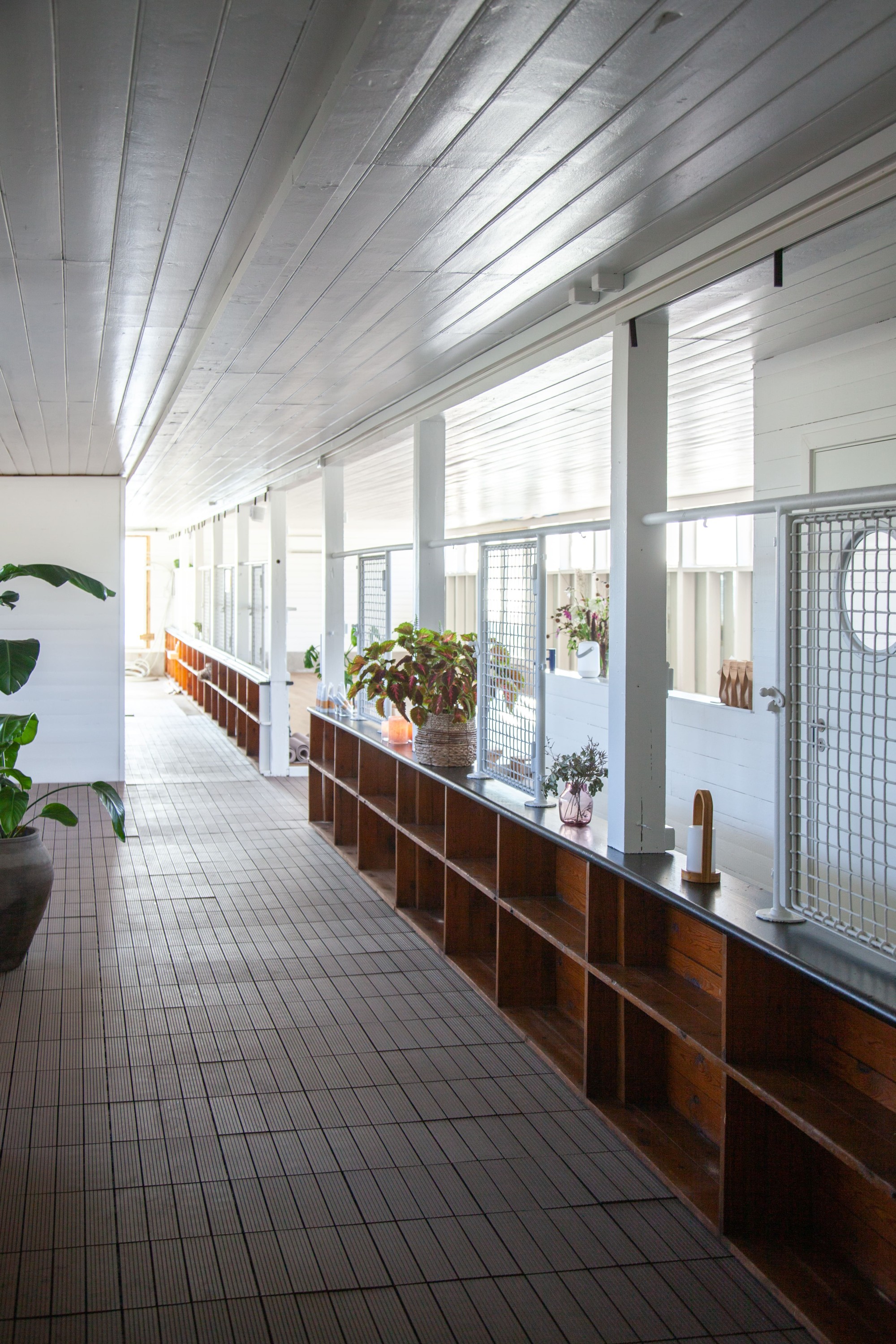 Lichtdurchfluteter Innenraum des Badehauses mit einem raumteilenden niedrigen Regal in der Mitte des Ganges