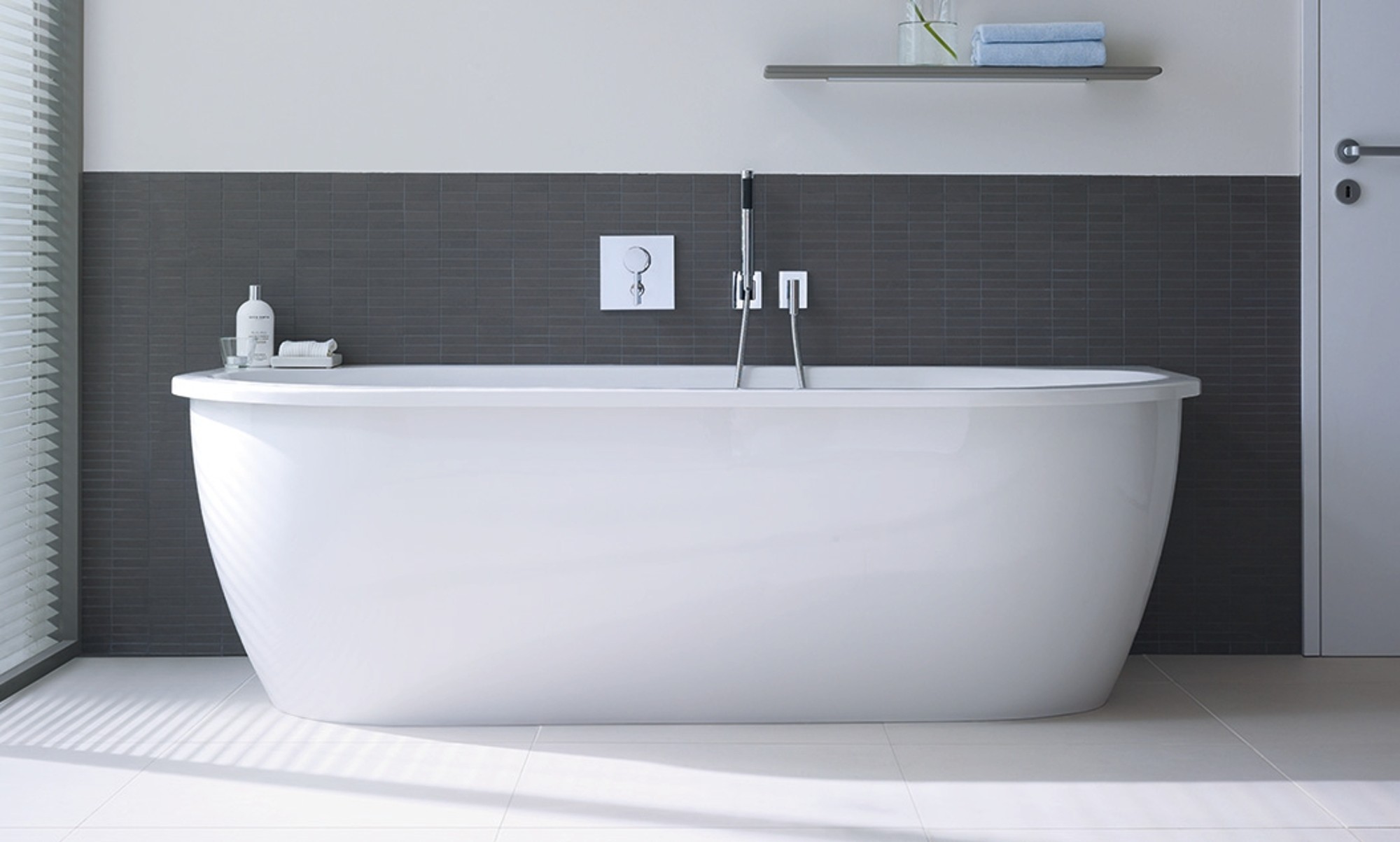 Freistehende Badewanne vor grauer Wand.
