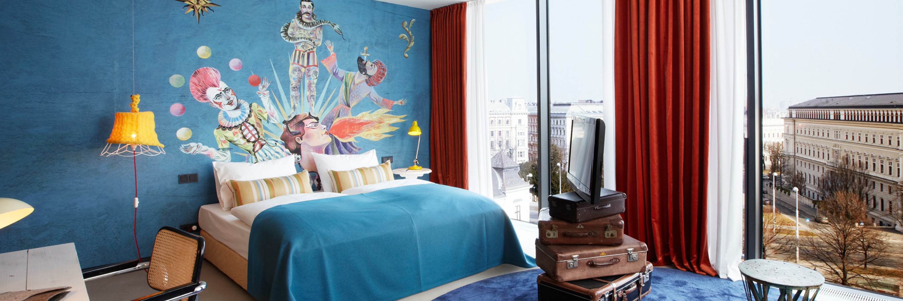 25hours Hotel Wien beim Museumsquartier, Hotelzimmer, Bett mittig, rechts Fenster, links Schreibtisch, bunte Einrichtung