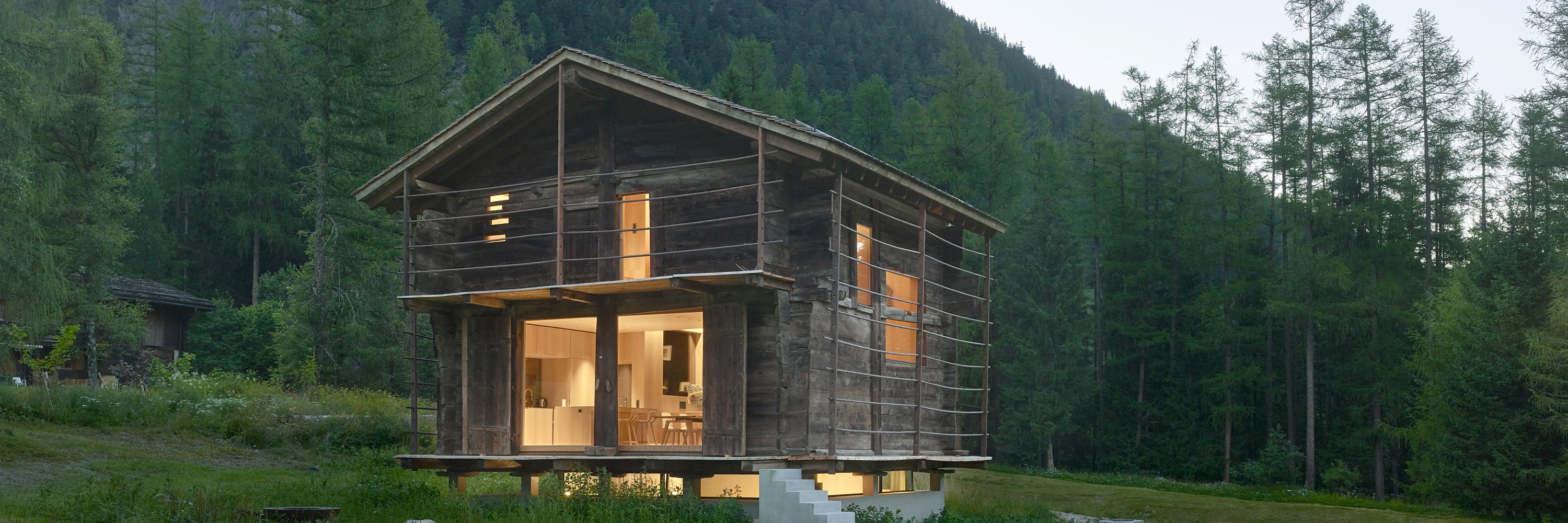 Chalet by Fabrizzi Architects, illuminated building from the outside with landscape