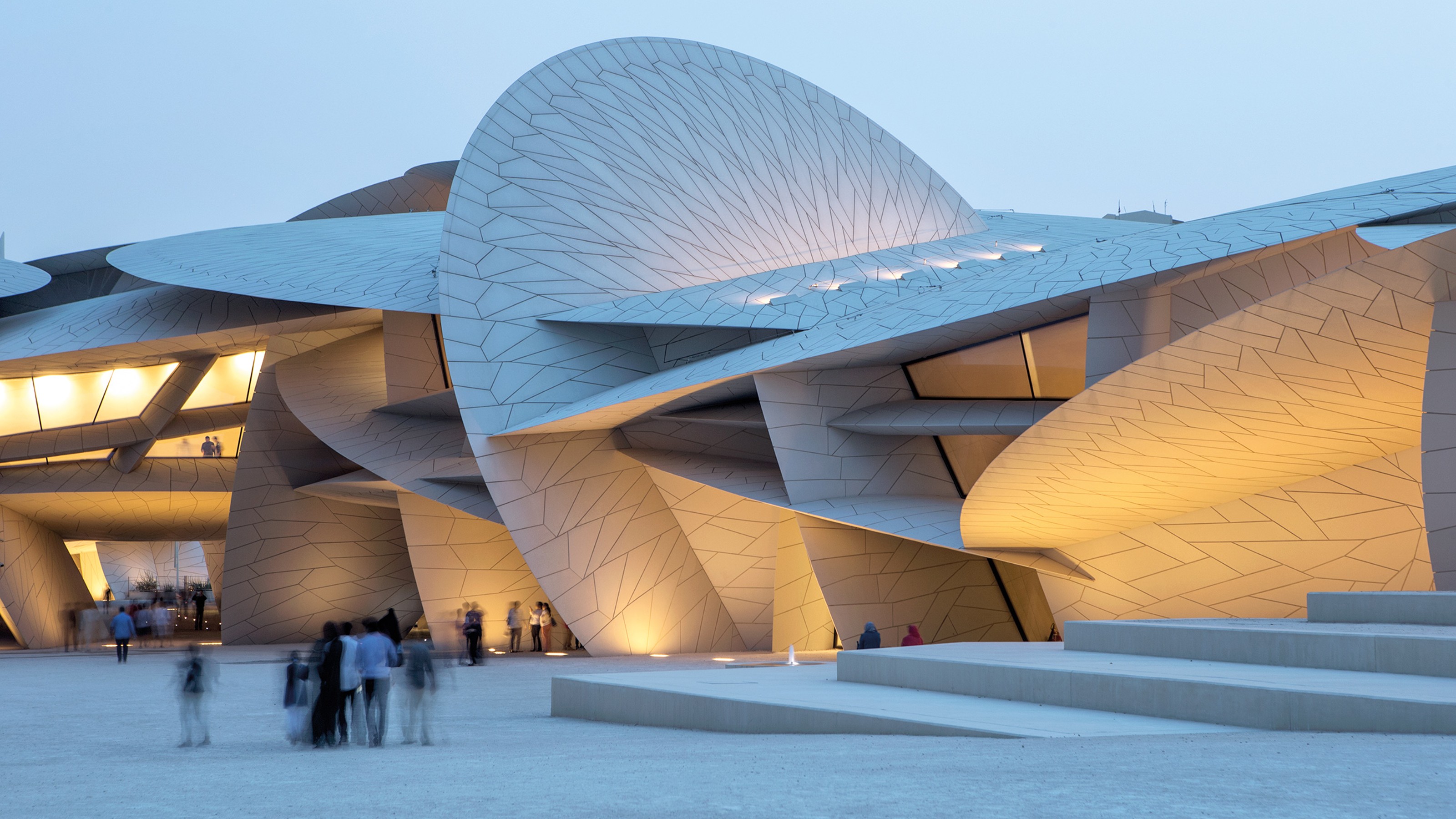 Qatar National Museum, illuminated exterior of the building at dusk with visitors