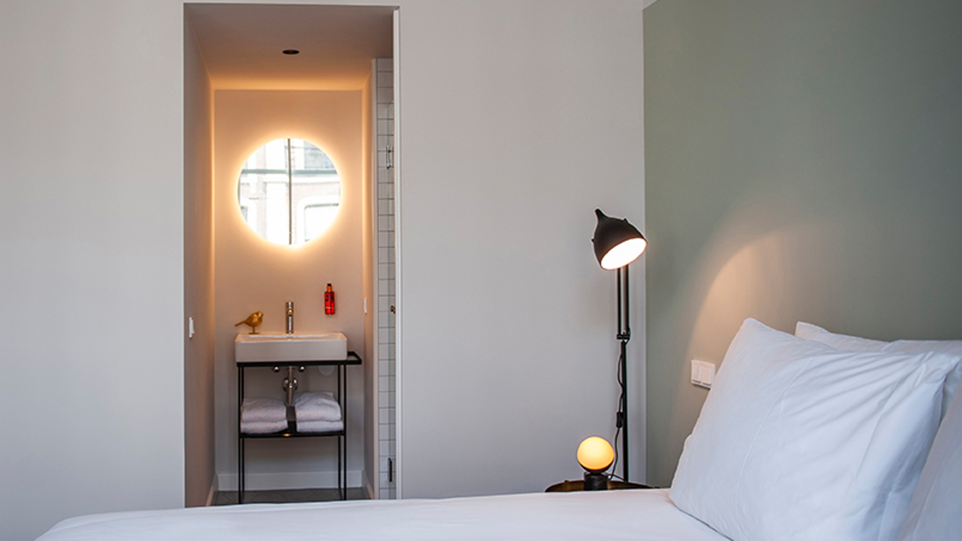 FINCH Boutique Hotel, hotel room with bed in the foreground and view of the washbasin in the bathroom through the door