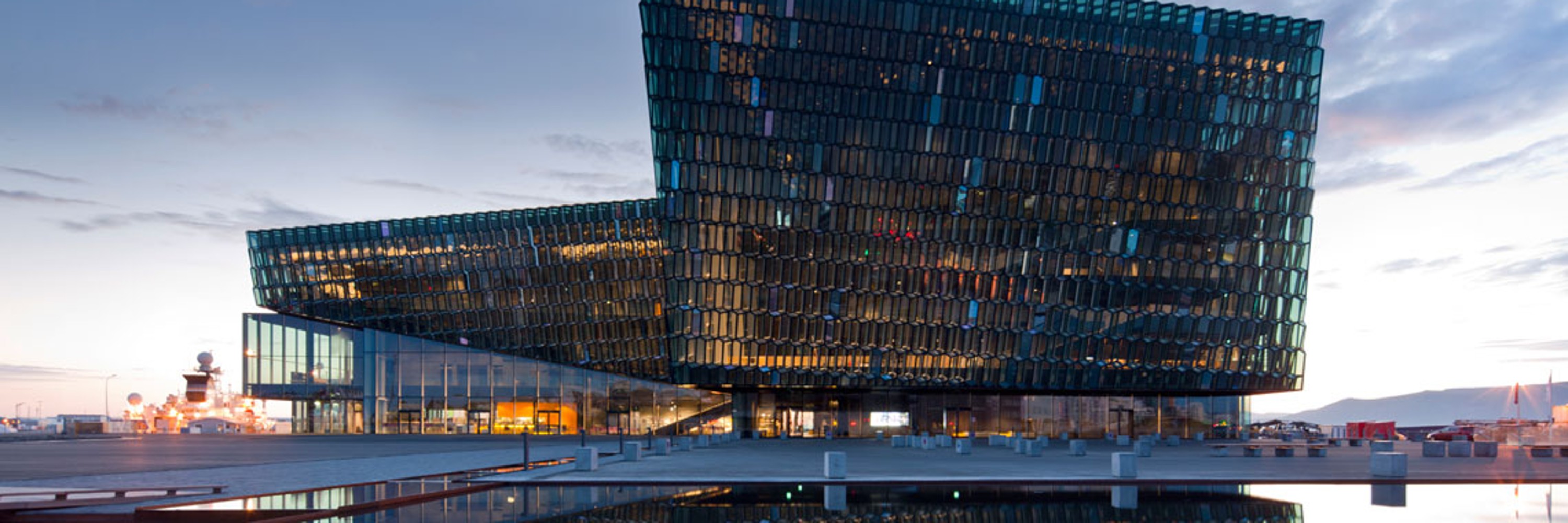 Harpa Concert Hall, exterior view at dusk, building reflected in the water in the foreground