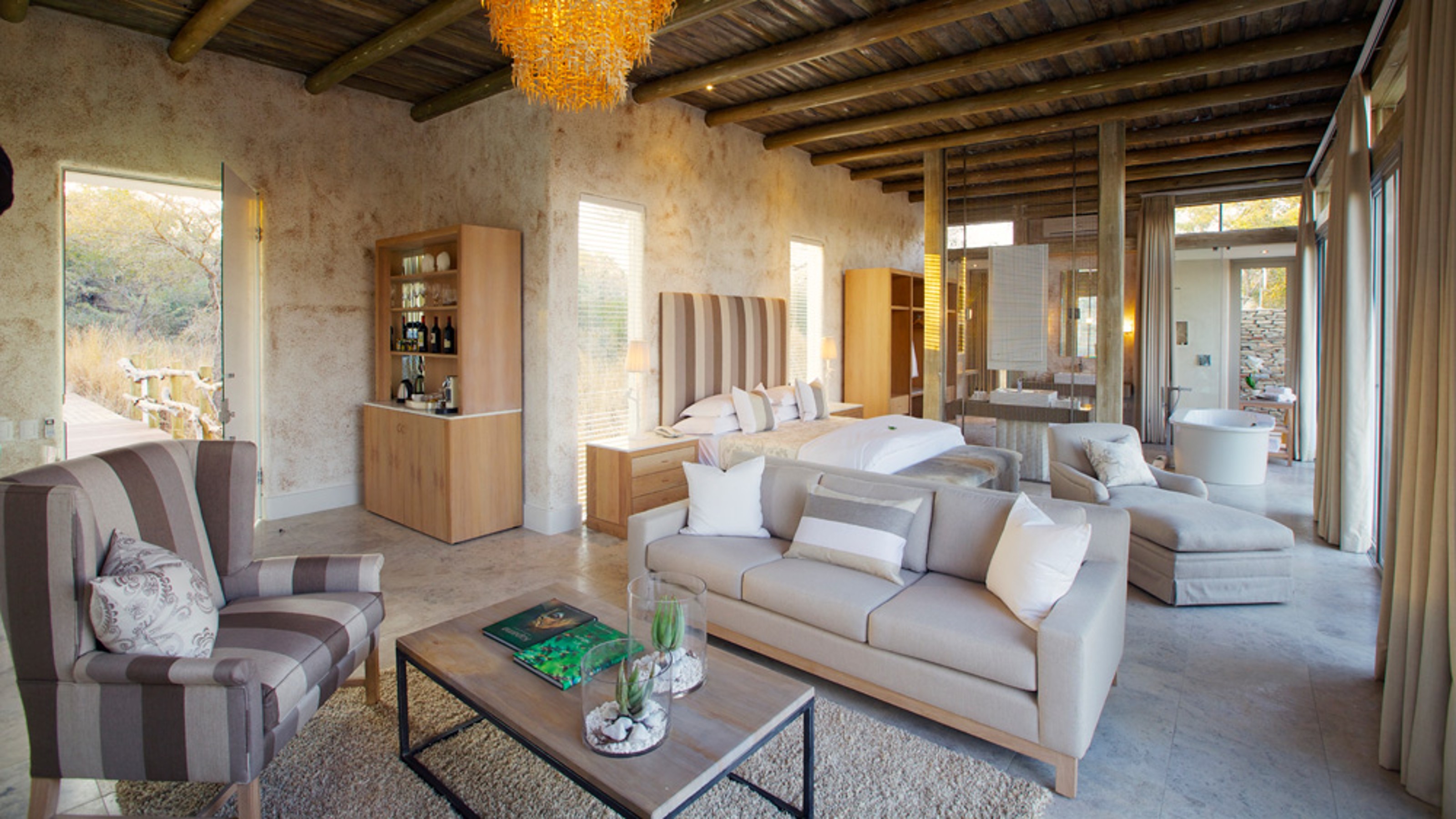 Kapama Karula Lodges, living room in the foreground, bed and open bathroom in the background