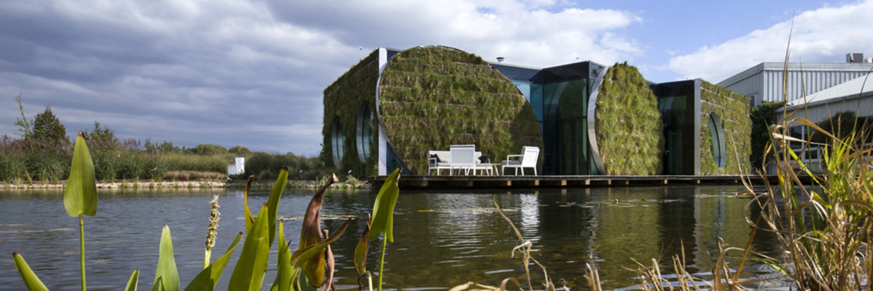 LIKO NOE, exterior view of the building with water and plants in the foreground