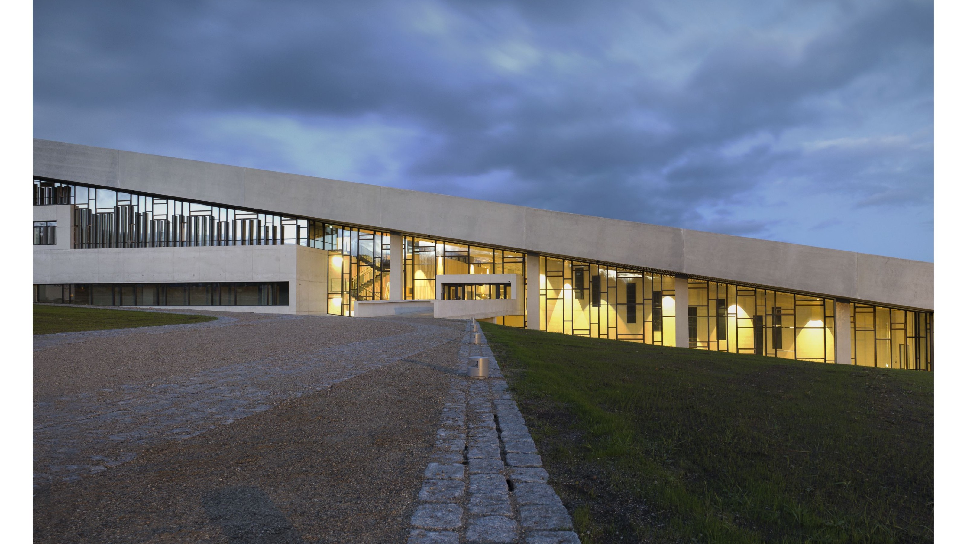 Moesgard Museum, photo of the illuminated building from the outside at dusk with a cloudy sky