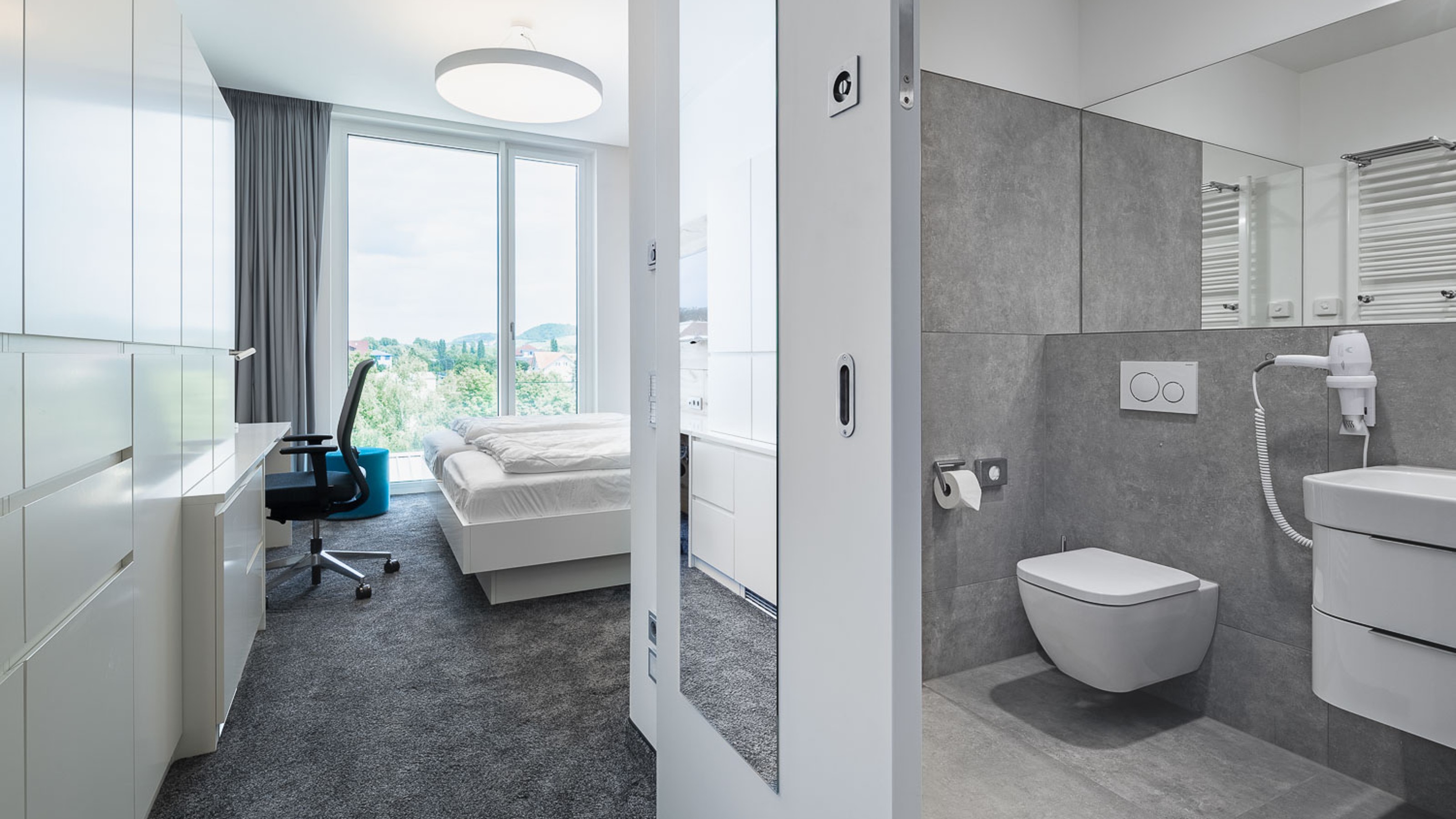 SLR Academy, room with view into the bathroom on the right and bed, wardrobe and desk on the left