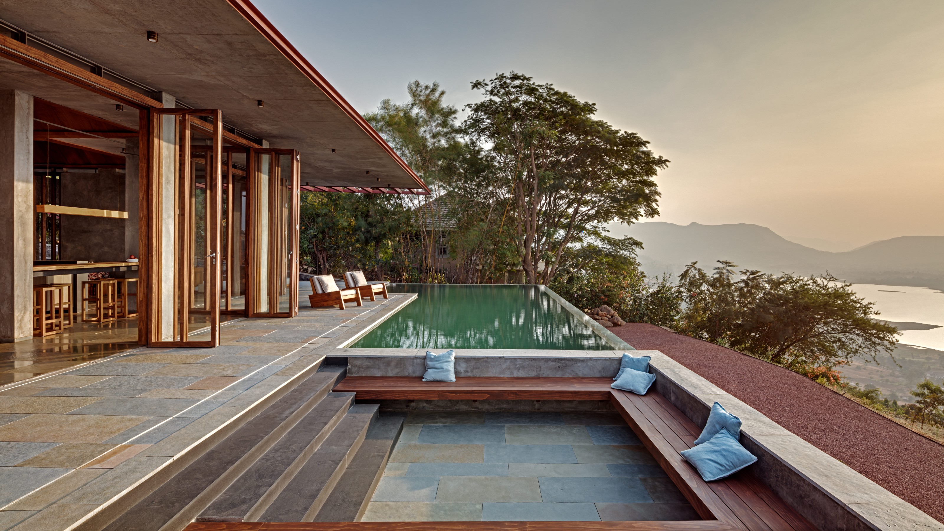 Sahyadri Mountain Resort, Gebäudeansicht von außen mit Pool und Sitzgelegenheit in der Mitte, rechts Blick aufs Wasser