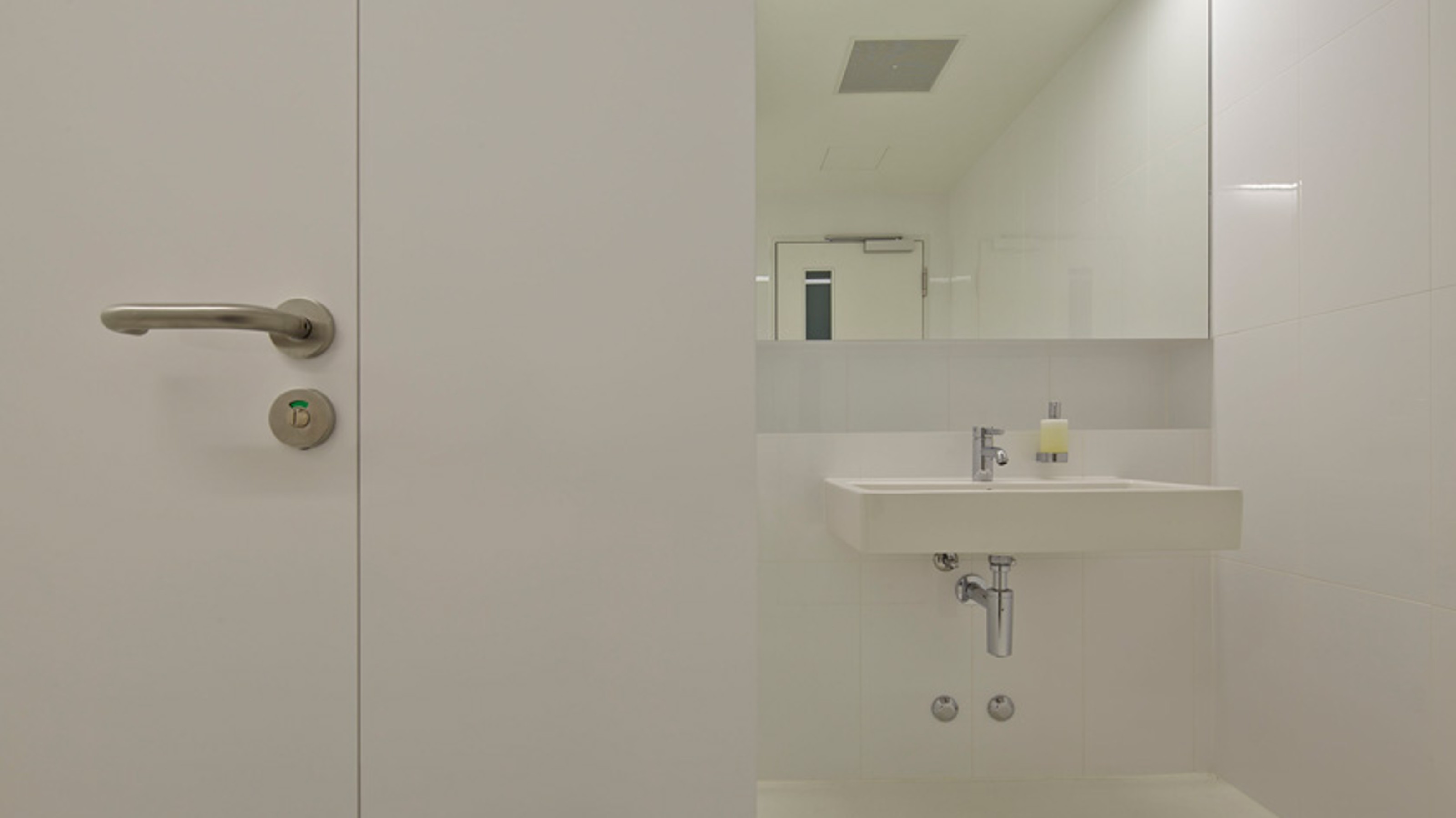 Tamedia publishing house, public toilet with washbasin on the right and toilet cubicle on the left
