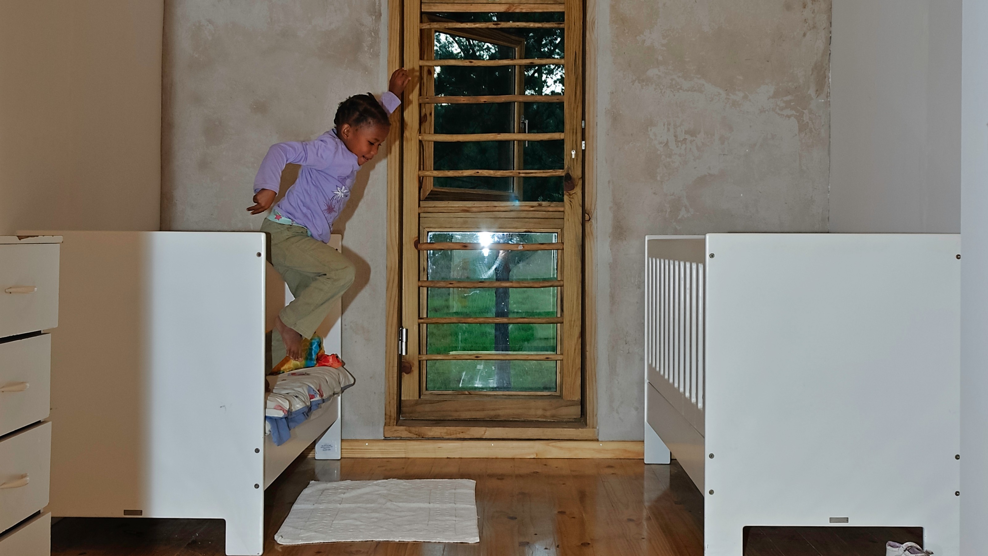 Ukuqala, bedroom with beds on the left and right, child jumping off the bed