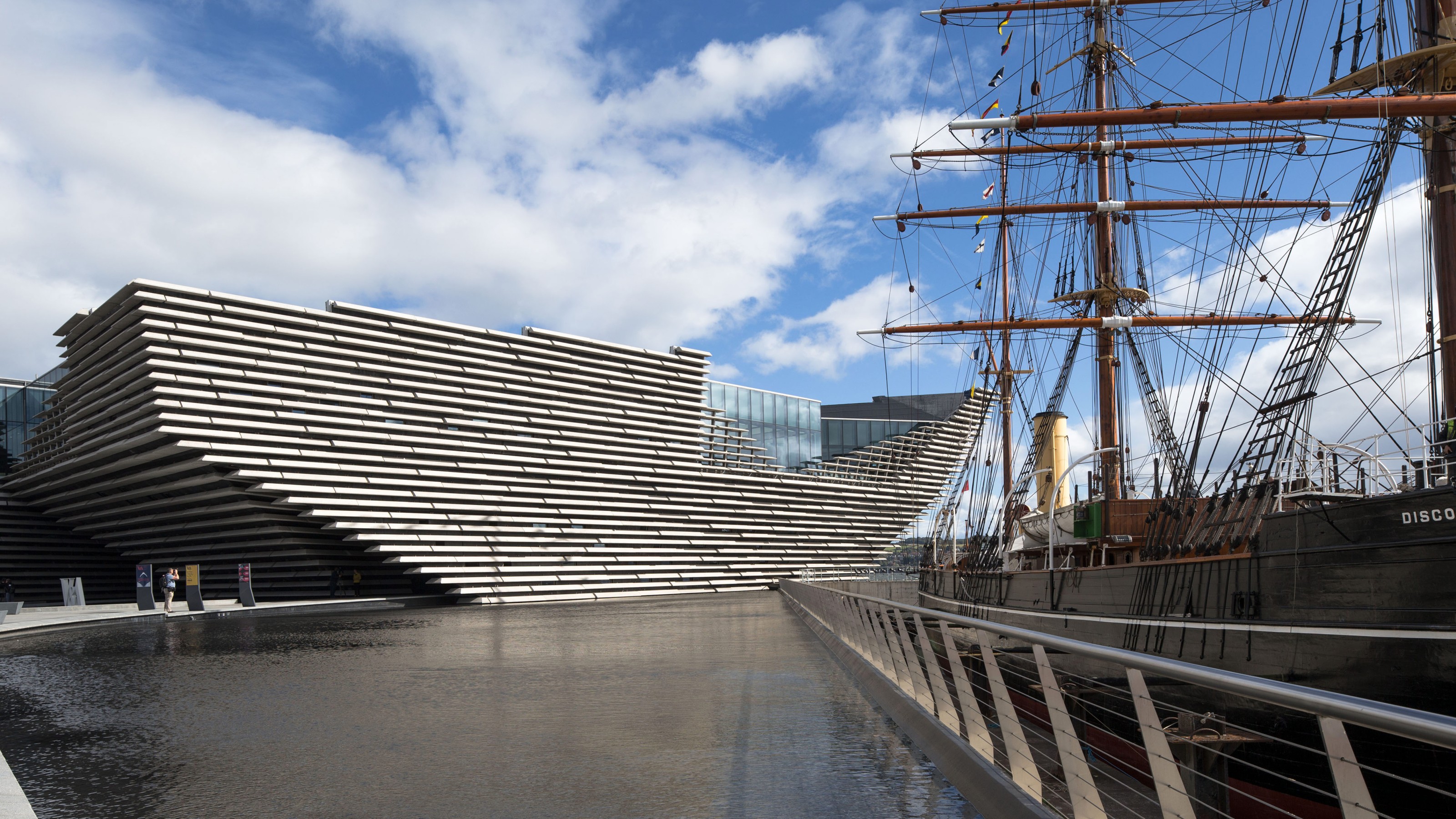 Victoria & Albert Museum Dundee, exterior view of the building, museum on the left, water in the foreground, ship on the right