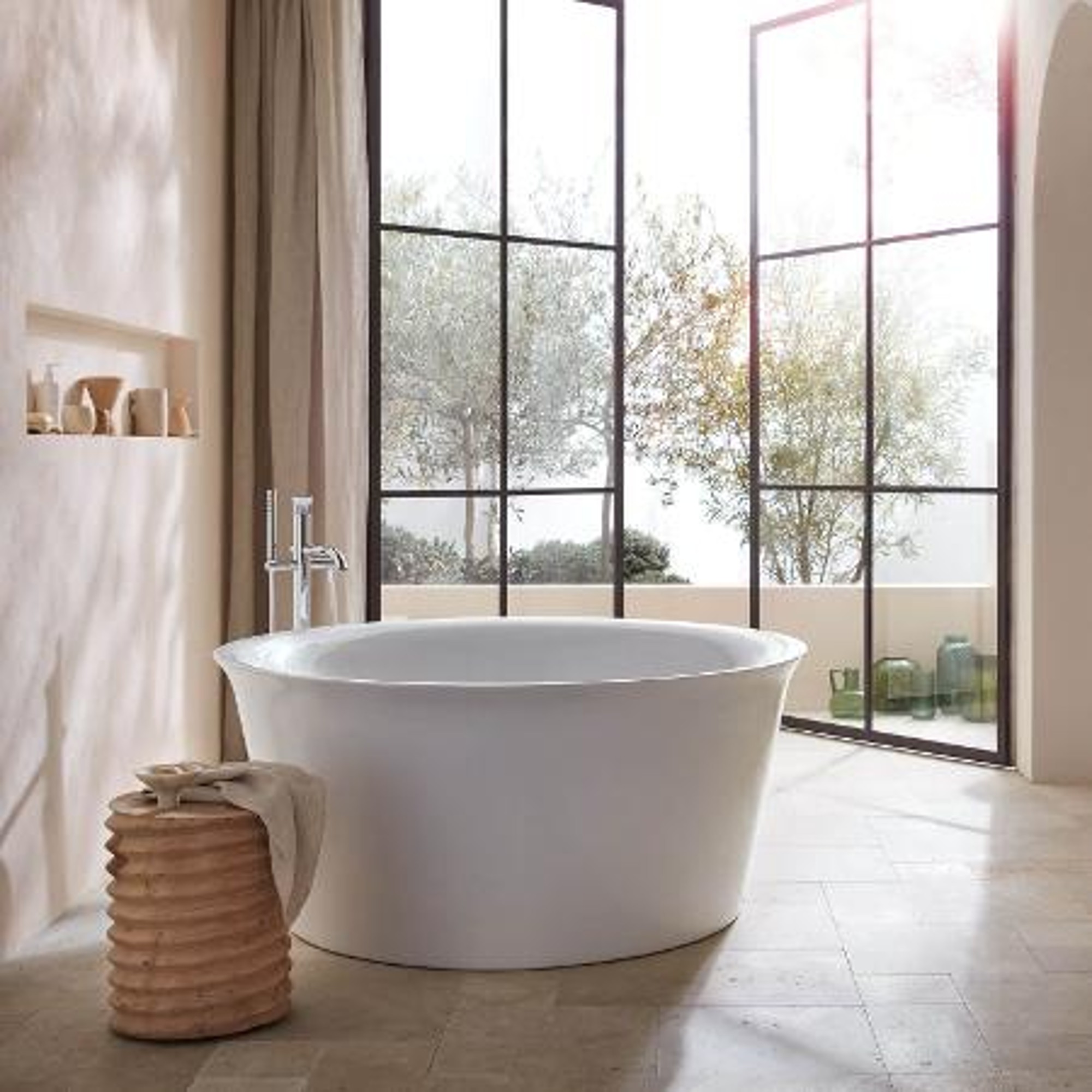 Freistehende Badewanne vor bodentiefen Fenstern.