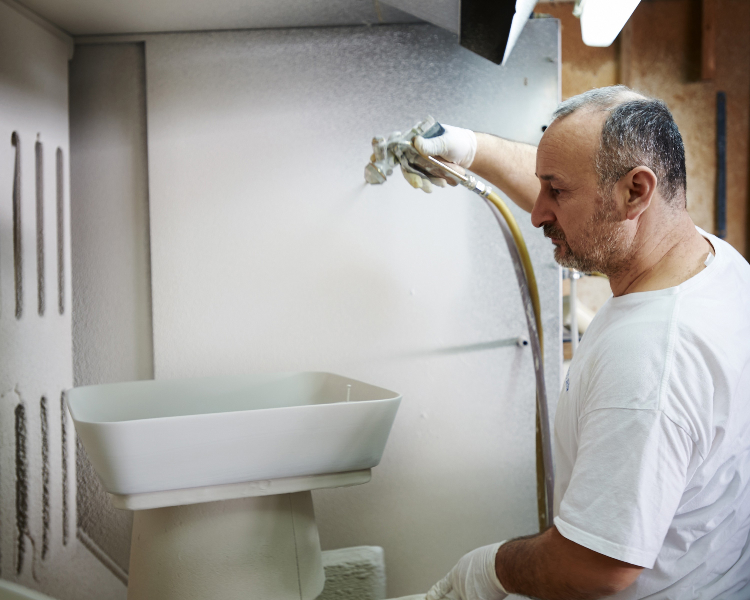 A man glazes ceramic sinks.
