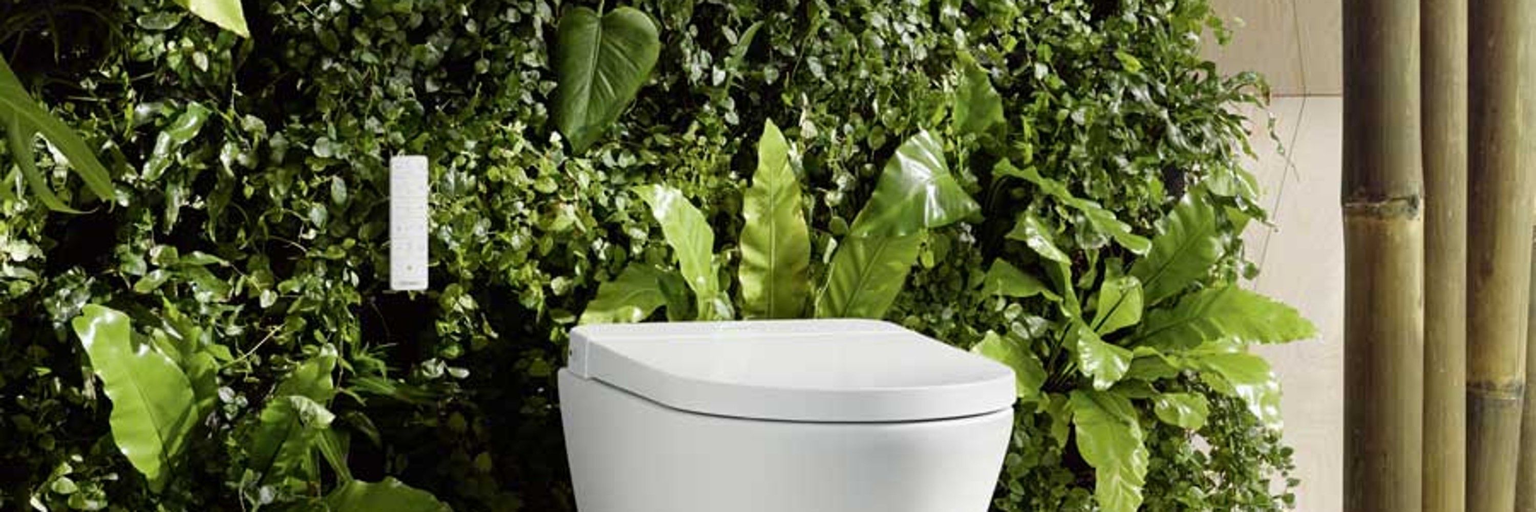 Inodoro con ducha de la serie Duravit SensoWash Slim rodeado de plantas de baño.
