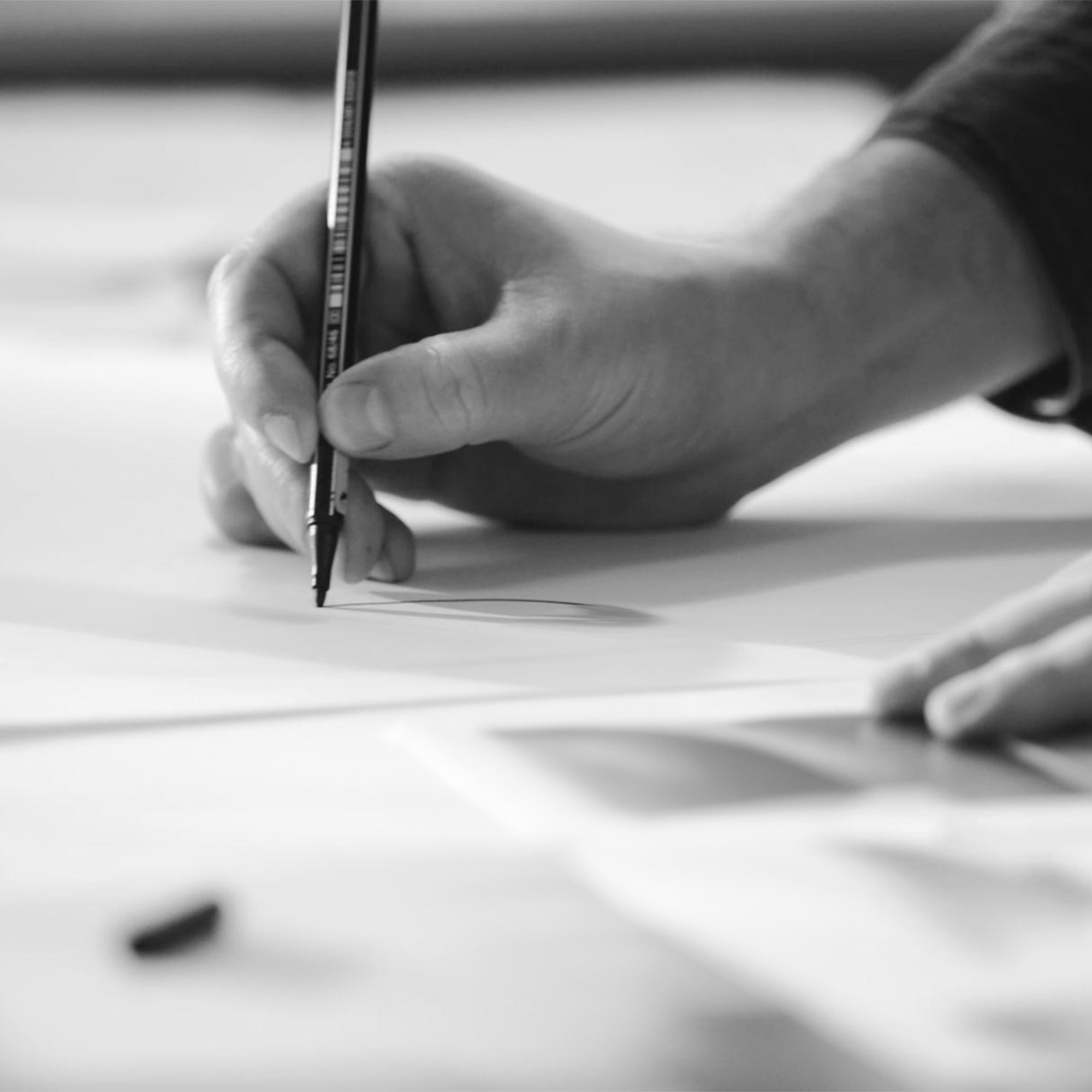 A hand draws with a pen on paper
