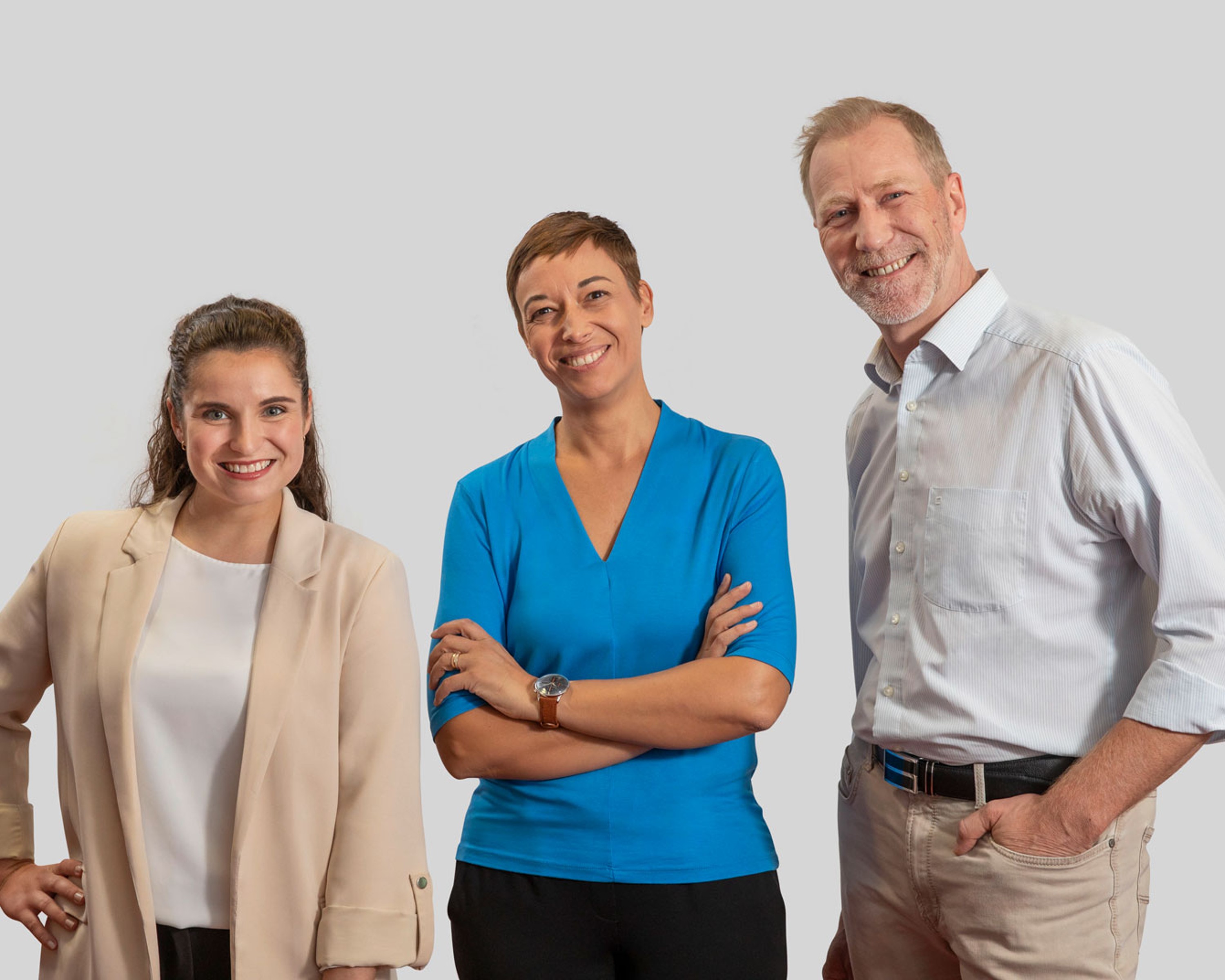 Drei Kolleg:innen die freudig beieinander stehen.