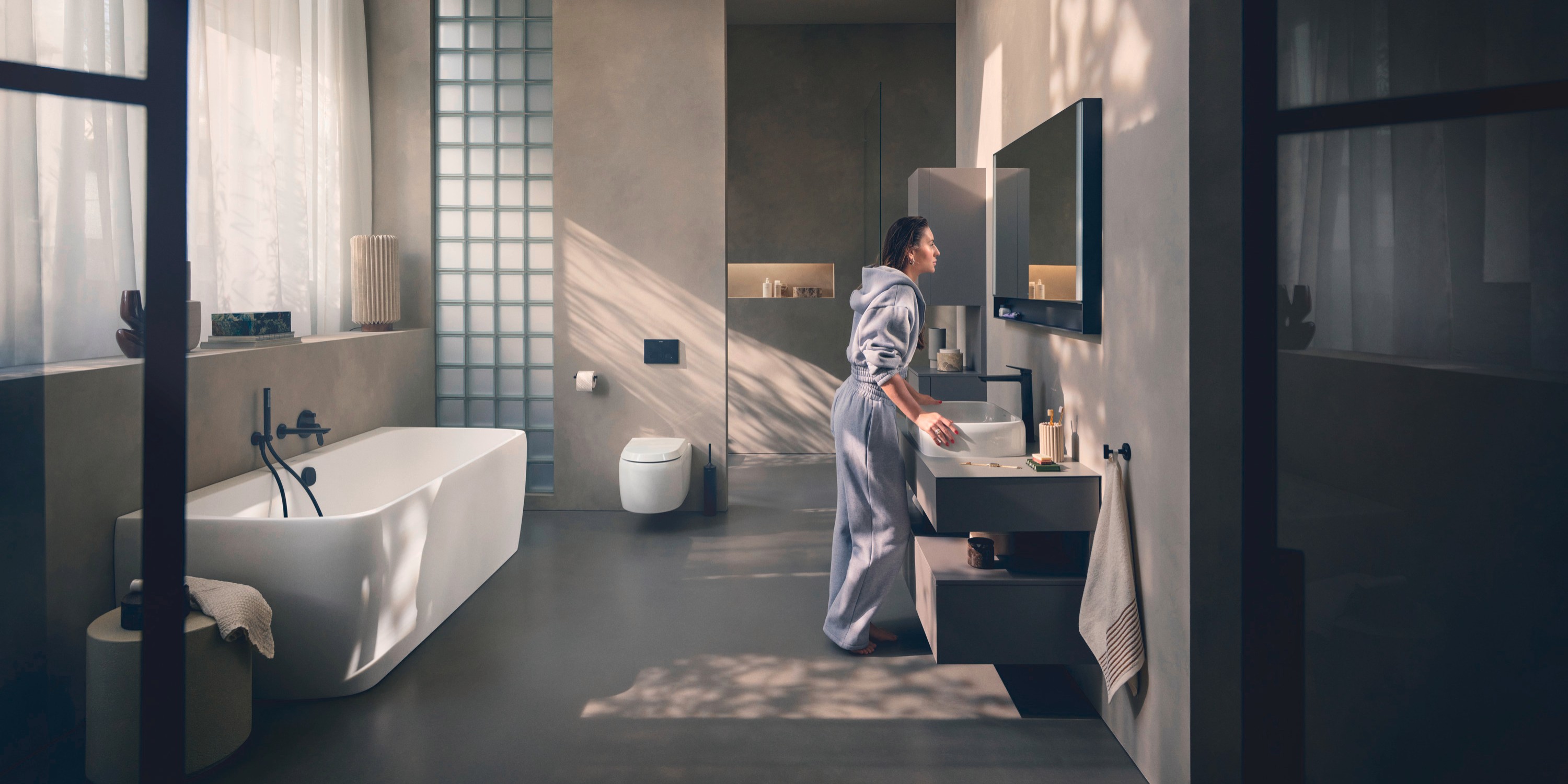 Eine Frau steht in einem modernen Bad am Waschplatz der Serie Collection One von Duravit