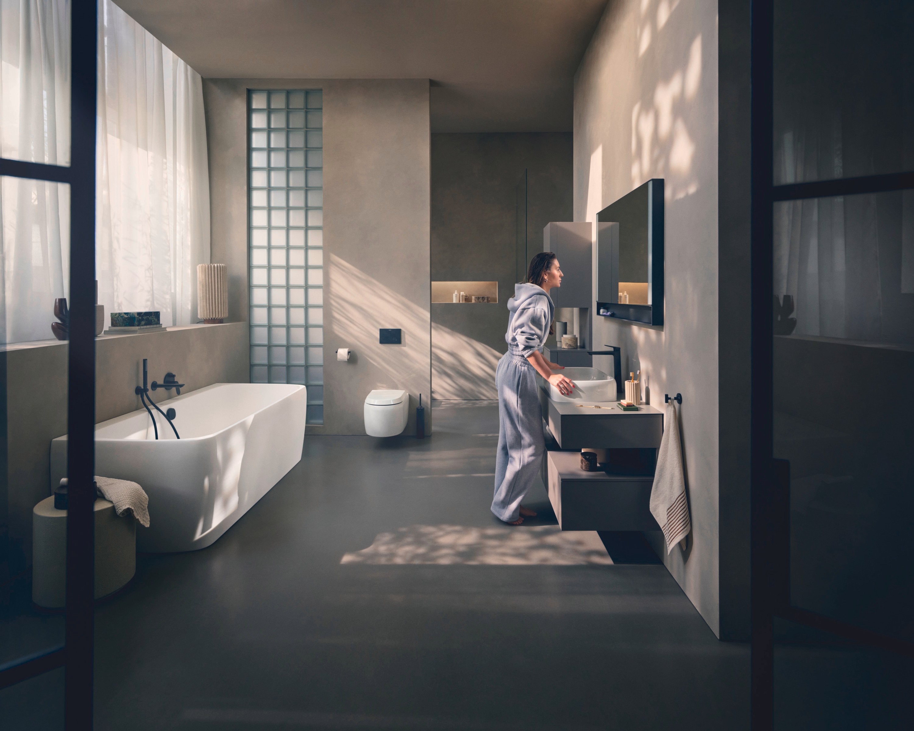 A person is standing in front of a mirror cabinet in a bathroom from the Collection One series