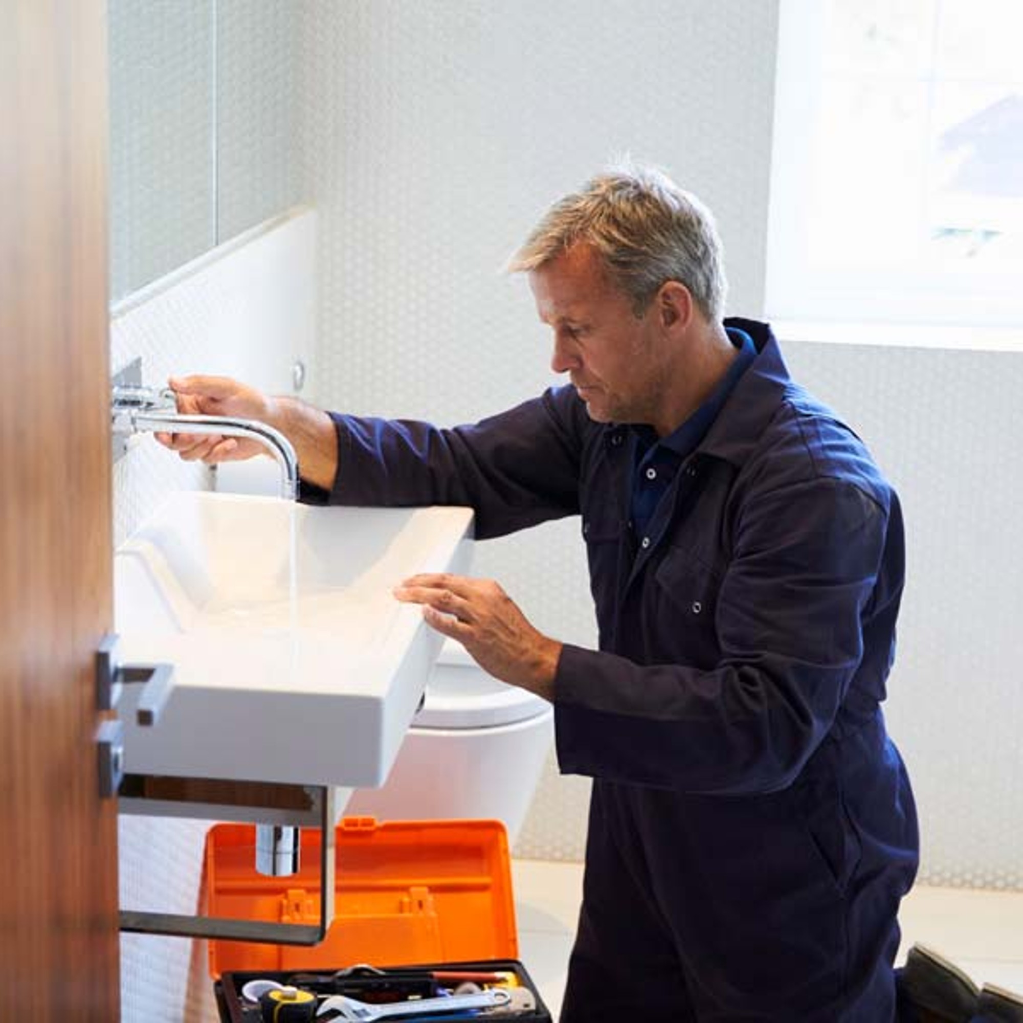 Technician installing a sink with wall-mounted faucet.