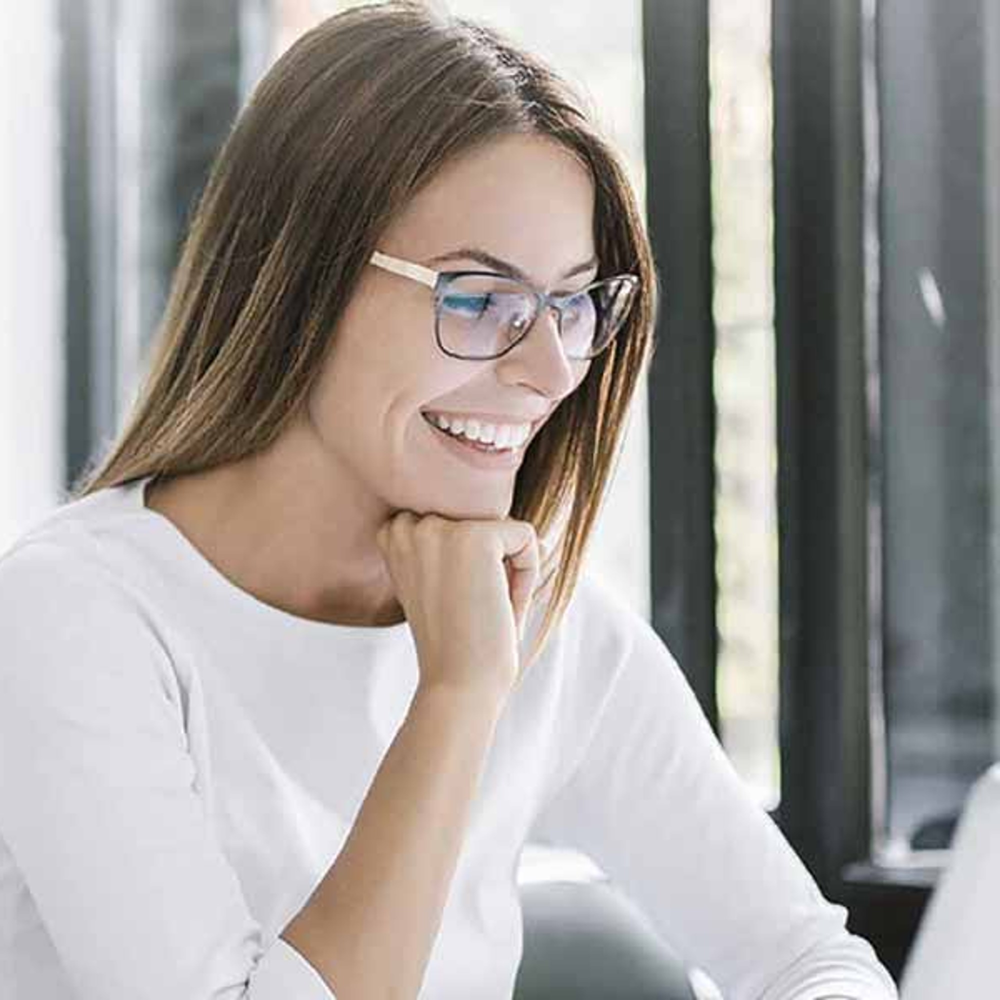 Une femme est assise devant un ordinateur portable, le sourire aux lèvres.
